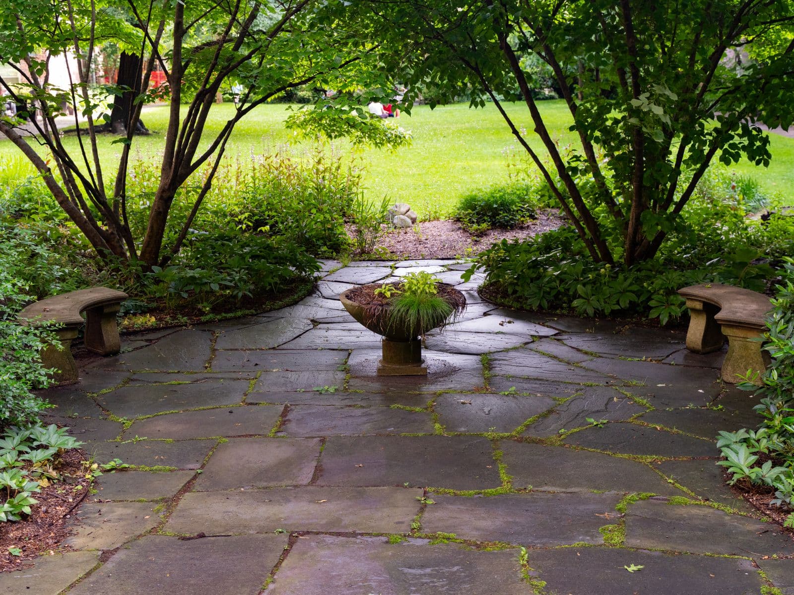A finished natural-stone patio surrounded by garden landscaping